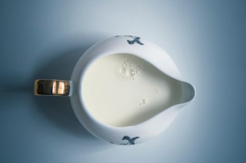 Blick von oben auf gefülltes Milchkännchen auf blauem Untergrund