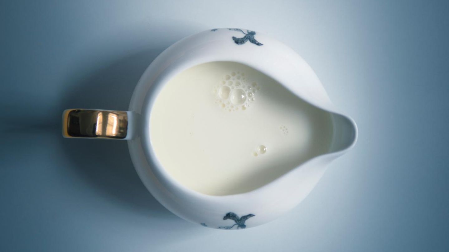 Blick von oben auf gefülltes Milchkännchen auf blauem Untergrund