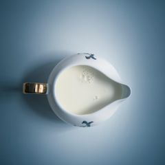 Blick von oben auf gefülltes Milchkännchen auf blauem Untergrund