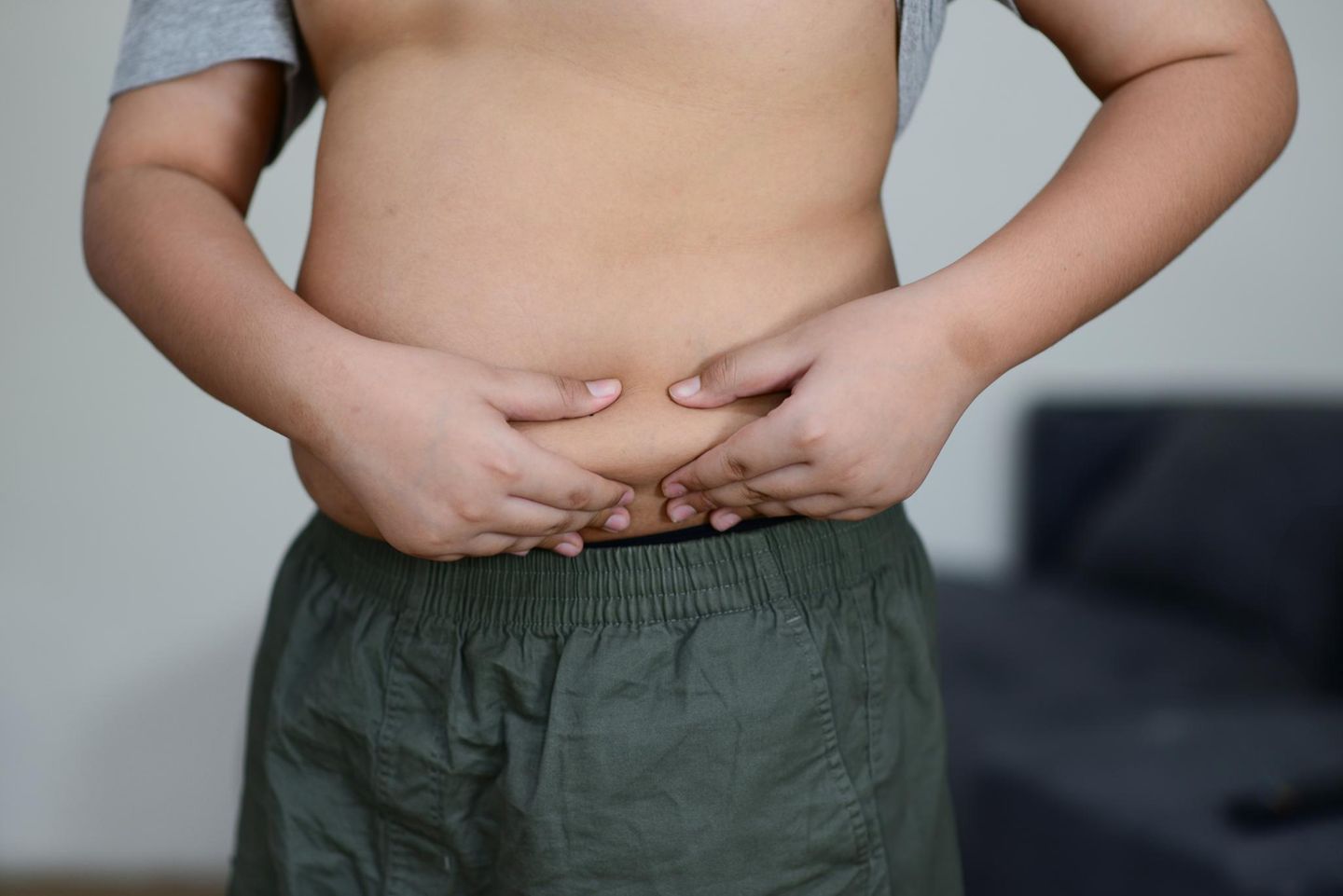 Ein Junge greift sich in seinen sichtbar fülligen Bauch