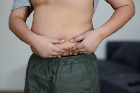 Ein Junge greift sich in seinen sichtbar fülligen Bauch