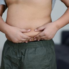 Ein Junge greift sich in seinen sichtbar fülligen Bauch