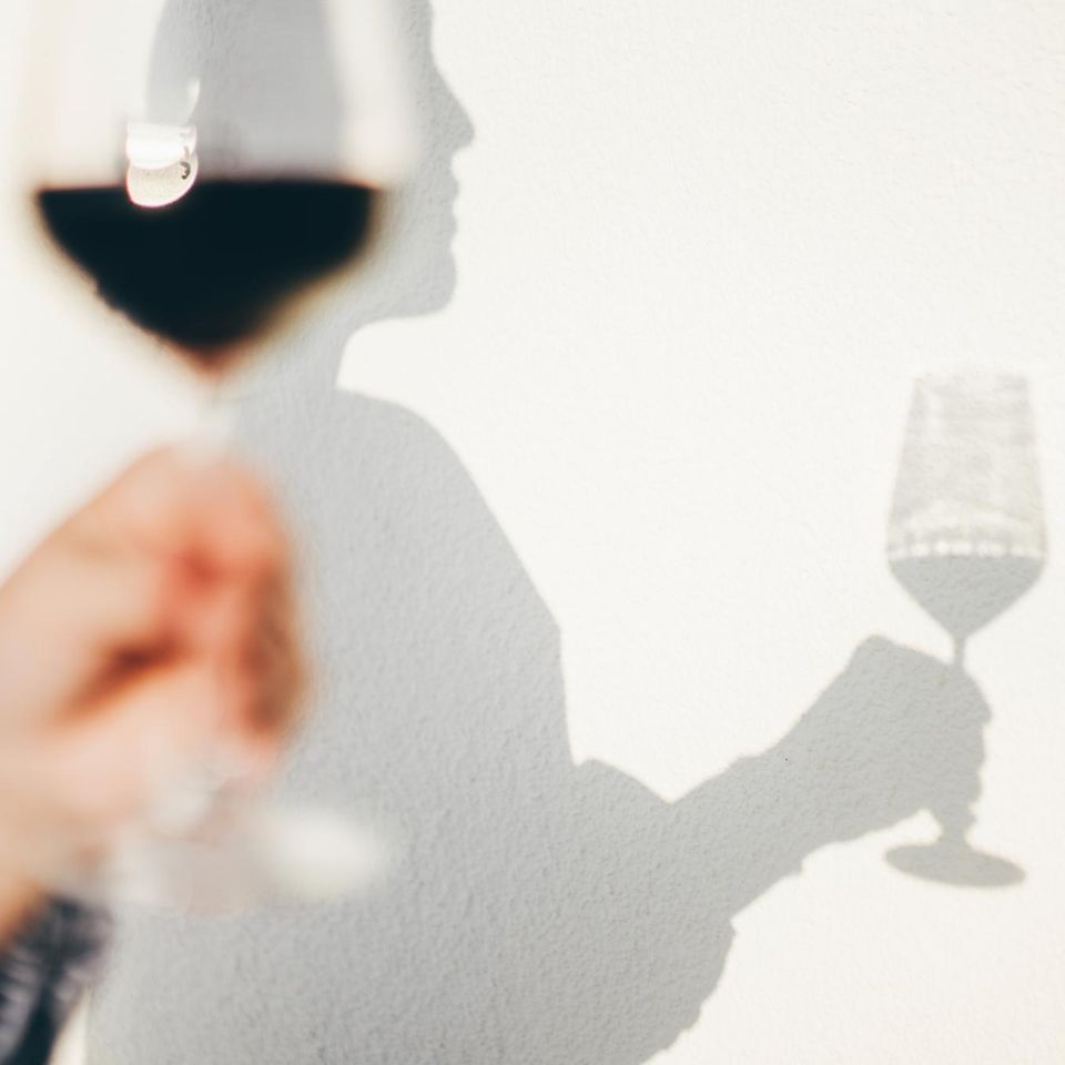 Wandschatten einer Person, die ein Weinglas in der Hand hält