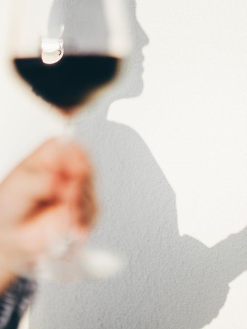 Wandschatten einer Person, die ein Weinglas in der Hand hält