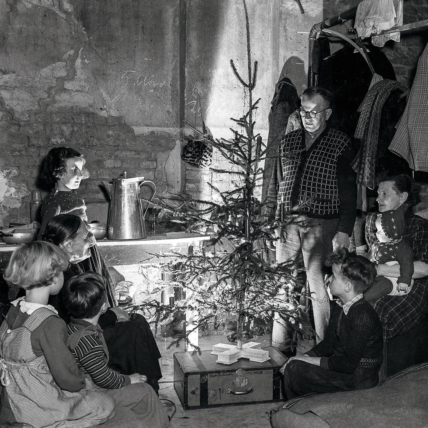 Familie sitzt um einen Weihnachtsbaum