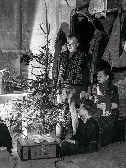 Familie sitzt um einen Weihnachtsbaum