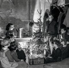 Familie sitzt um einen Weihnachtsbaum