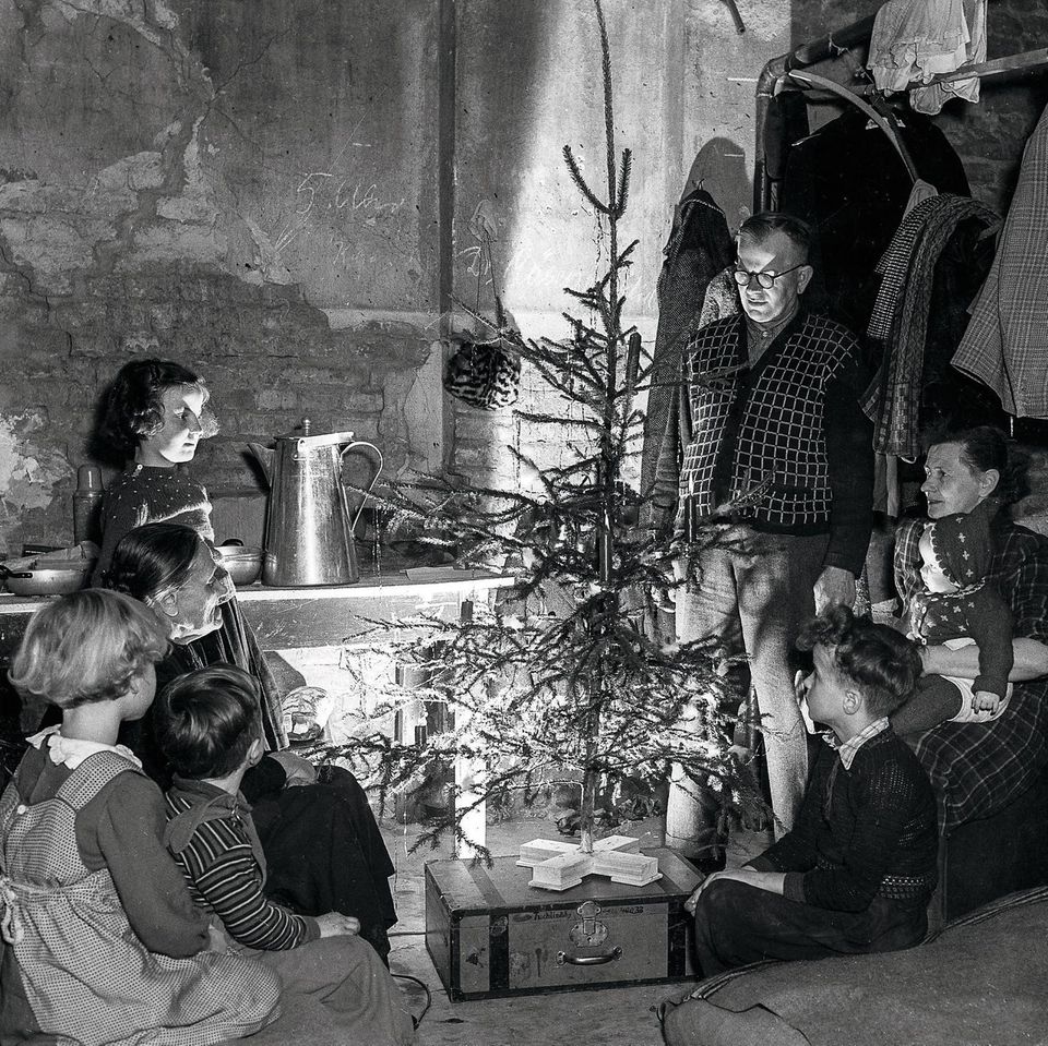 Familie sitzt um einen Weihnachtsbaum