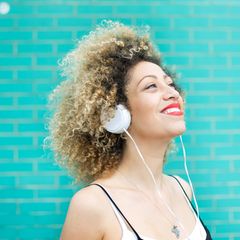 Junge Frau hört Musik mit Kopfhörern und lächelt