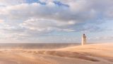 Nahe dem kleinen Ort Lønstrup an der nordjütischen Westküste finden Reisende eine wahre Ikone: den Leuchtturm von Rubjerg Knude. Schon von Weitem sichtbar, thront er auf einer der größten Wanderdünen Europas und ist eines der bekanntesten Wahrzeichen Nordjütlands. Einst 200 Meter von der Küste entfernt errichtet, kämpft er bis heute gegen die beständige Kraft von Wind, Sand und Meer. Im Oktober 2019 wurde der 23 Meter hohe Turm deshalb spektakulär um 80 Meter landeinwärts versetzt, weil die stetige Erosion ihn an den Rand der Steilküste gedrängt hatte. Wer den Turm erklimmt, wird mit einem atemberaubenden Ausblick über die raue See und die Steilküste belohnt. 