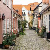 Die Hauptstadt Nordjütlands fasziniert mit Kontrasten: Aalborg liegt malerisch am Limfjord und besticht mit farbenfrohen Häuschen und Gassen. Wer historisches Flair sucht, findet das beispielsweise in der Winkelstraße Hjelmerstald. Einst im 17. Jahrhundert als Pferdestallgasse entstanden, entdecken Reisende dort heute ein lebhaftes Wohnviertel mit viel Charme und Geschichte vor. Doch Aalborg, oft liebevoll als "Paris des Nordens" bezeichnet, bietet auch moderne Highlights: So ist die spektakulär gestaltete Konzerthalle an der Uferpromenade, das Musikkens Hus, in jedem Fall einen Besuch wert. Gleich um die Ecke befindet sich das futuristisch anmutende Utzon Center, errichtet zu Ehren von Jørn Utzon – Aalborgs berühmtester Sohn entwarf das ikonische Opernhaus in Sydney, woran das Kulturcenter im kleinen Maßstab erinnert.