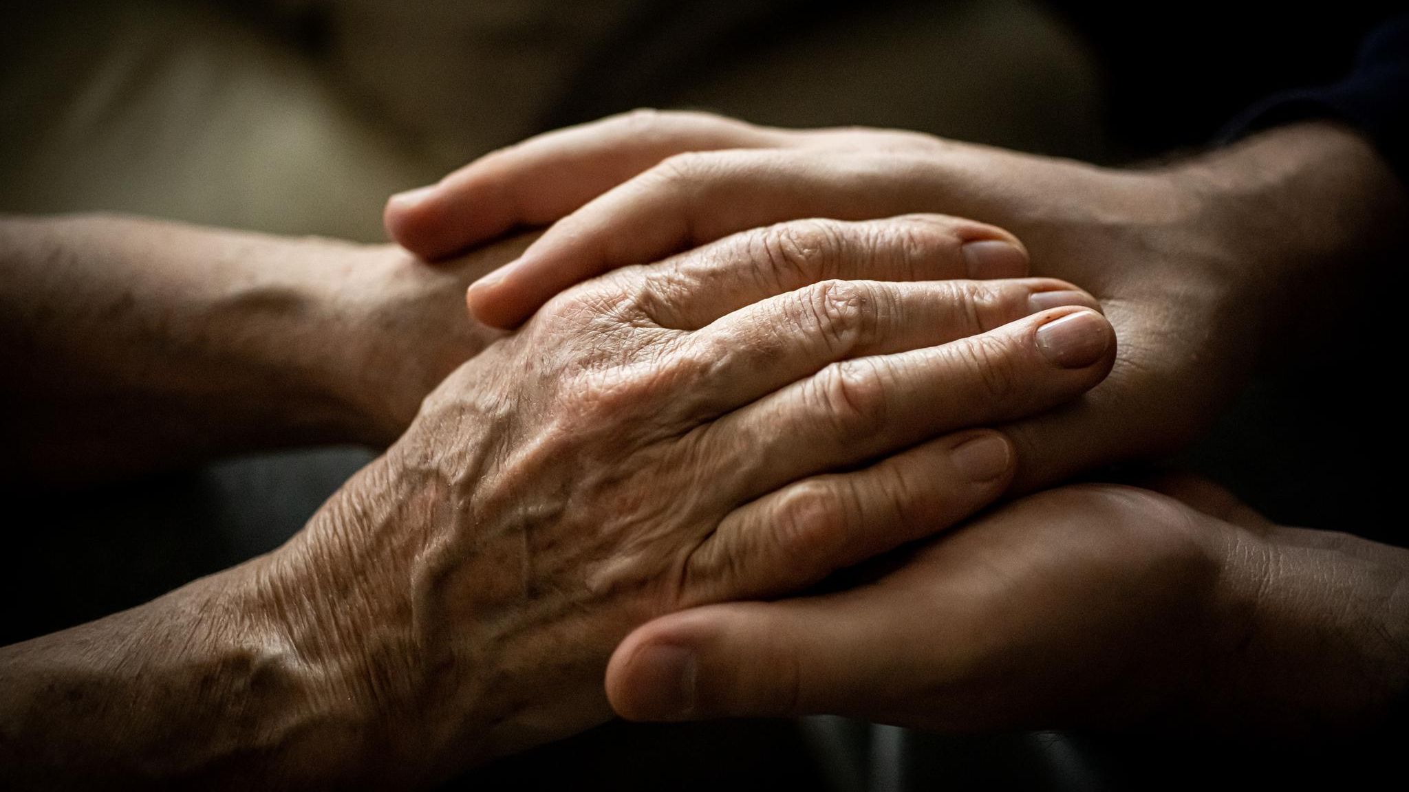 Junge Frau hält die Hände einer alten Frau