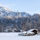 Schloss Neuschwanstein, umgeben von Bäumen, im Vordergrund Häuser