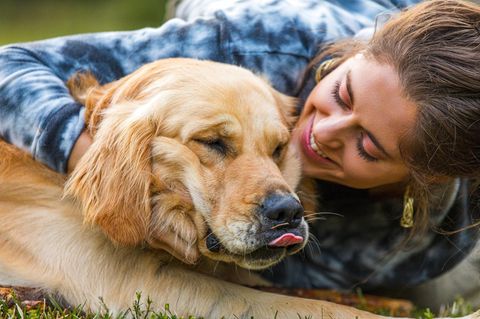 Junge Frau spielt glücklich mit ihrem Golden Retriever