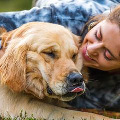 Junge Frau spielt glücklich mit ihrem Golden Retriever