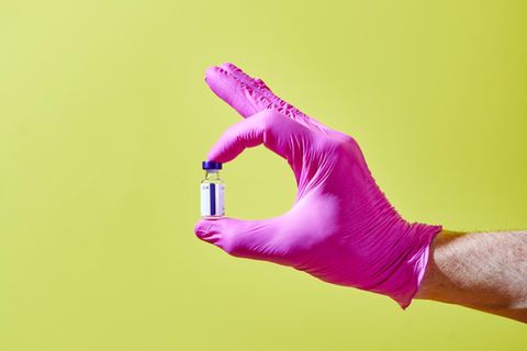 Eine Hand hält ein Fläschchen mit Impfstoff