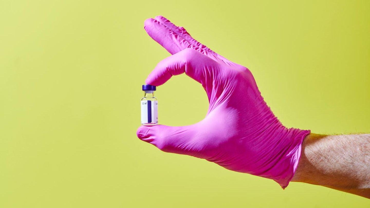 Eine Hand hält ein Fläschchen mit Impfstoff