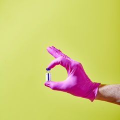 Eine Hand hält ein Fläschchen mit Impfstoff