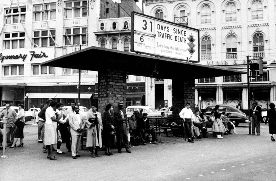 Eine Gruppe Afroamerikaner stehen an einer Bushaltestelle