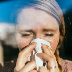 Grippevirus: eine Frau putzt sich die Nase