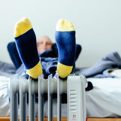Mann wärmt seine Füße auf einer kleinen Heizung