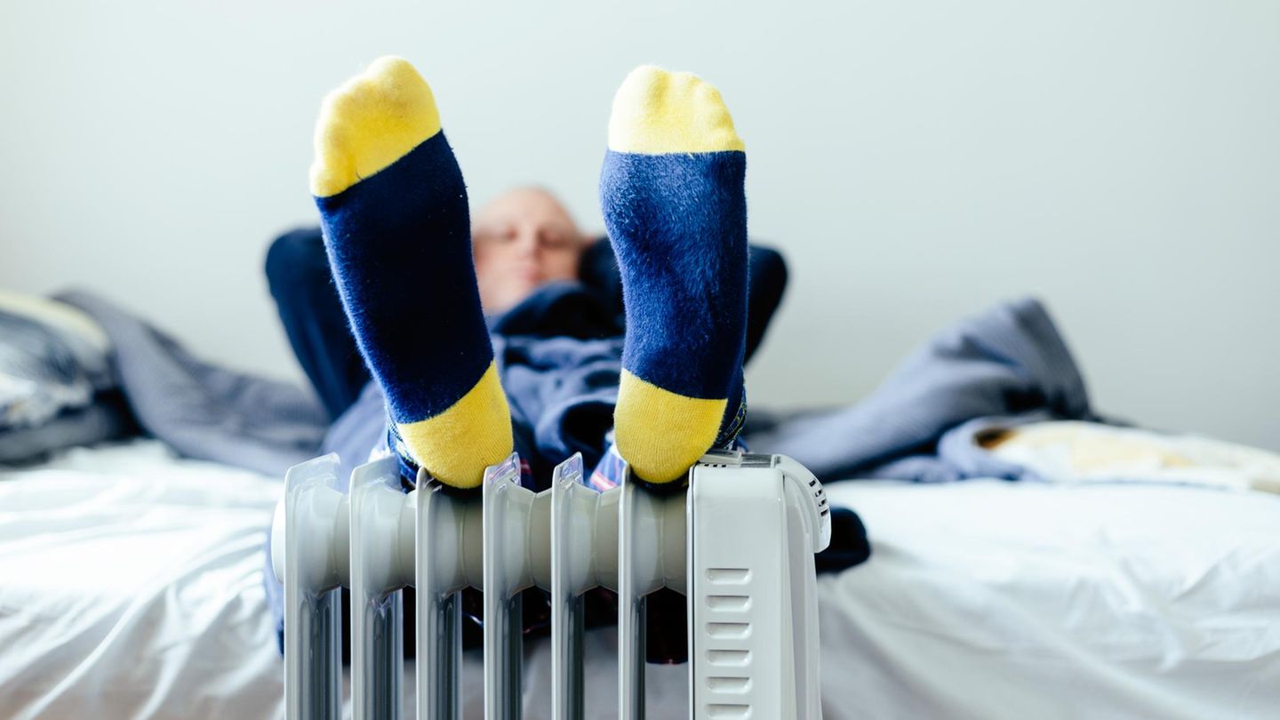 Mann wärmt seine Füße auf einer kleinen Heizung