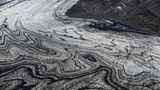 Wenn sich Gletscherströme ihren Weg durch das Gebirge bahnen, verschlägt ihre schiere Kraft den Betrachtenden meist den Atem. Die schwarze Vulkanasche, die das Eis des Skeidararjökull hier marmoriert, zeugt jedoch von einem noch gewaltigeren Naturspektakel: dem Wechselspiel zwischen Schnee und Feuer, Sonne und Wind. "Die Vulkaneruptionen liefern die schwarze Asche, welche die Gletscher überdeckt. Darauf fällt frischer Schnee, der allmählich zu Eis komprimiert wird. So legt sich weiße auf schwarze Schicht, viele Male", beschreibt die Geologin Angelika Jung-Hüttl das Phänomen. Je weiter sich der Gletscher seinen Weg ins Tal bahnt, desto verwobener sind die beiden Schichten, desto schwungvoller die Muster.