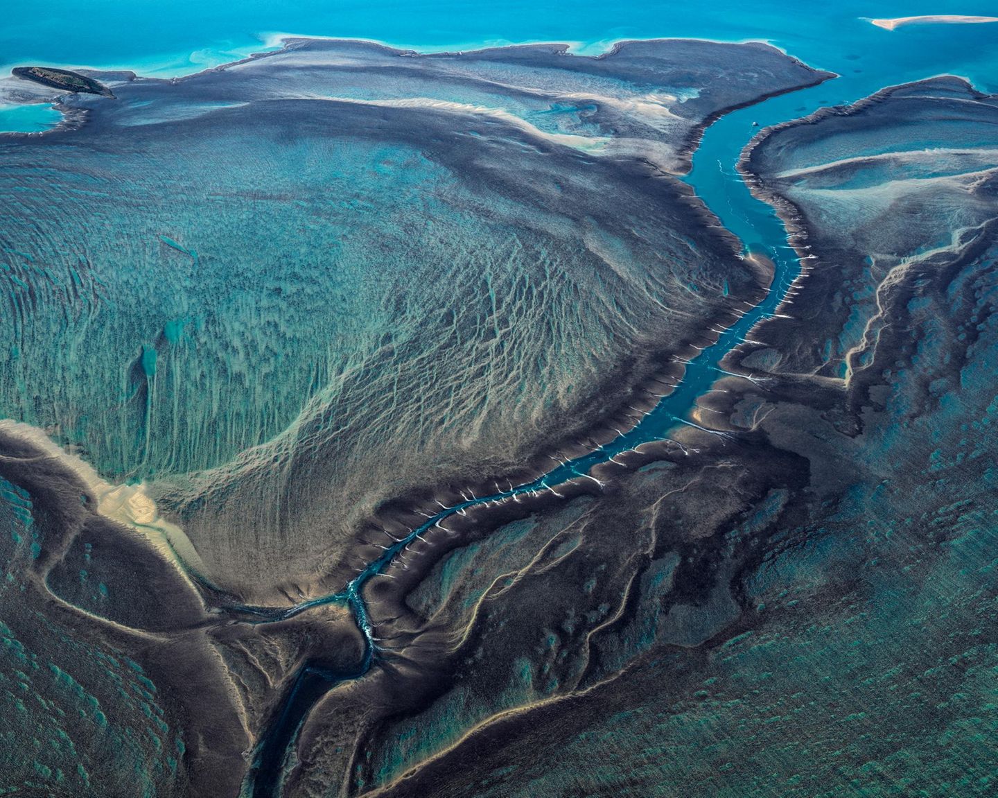50 Arten Türkis: So leuchtet das Wasser des Montgomery Riff vor der Nordwestküste Australiens. Die Strahlkraft verändert sich je nach Wasserstand, der Tidehub zwischen Niedrigwasser und Hochwasser beträgt hier rund zehn Meter: Bei Ebbe ragt das Riff aus dem Wasser, bei Flut verschwindet es komplett. "Bei Flut liegen Riffplattform und Gezeitenkanal – gleichmäßig überspült– knapp unter dem Meeresspiegel. Bei Ebbe jedoch, wenn der Meeresspiegel innerhalb weniger Stunden tief fällt, fließt das Wasser schneller aus dem großen Gezeitenkanal ab, als es von der Plattform nachfließen kann", schreibt die Geographin Angelika Jung-Hüttl. Dann stürzt es dem Kanal in Wasserfällen über die Riffkante entgegen, die das Riff von oben betrachtet mit Narben übersäen. Der spektakuläre Anblick bleibt den Riffbewohnern verborgen, die sich im vom Gezeitenwechsel bestimmten Lebensraum tummeln: Meeresschildkröten, Wale, Riffhaie, Mantarochen und Salzwasserkrokodile. 