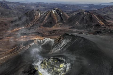 Wie eine eiternde Wunde klafft der Vulkankrater auf dem Gipfel des Isluga, der sich über der kahlen Landschaft des Altiplano an der Grenze zwischen Chile und Bolivien erhebt. Gasschwaden treten aus seinem Inneren; gelb gefärbtes Gestein an den Kraterwänden bezeugt die Schwefelvorkommen, die hier vor einigen Jahrzehnten noch abgebaut wurde. Bernhard Edmaier fotografierte den gewaltigen Krater mit einem Durchmesser von 400 Metern aus der Vogelperspektive und dabei Wissenschaft und Kunst vereint. Der Fotograf und Geologe zeigt mit seinen spektakulären Luftaufnahmen im Bildband "Elements", mit welcher Macht die Natur Landschaften formt – nicht nur hier, in der Hochebene der Anden, sondern auf allen Kontinenten.  