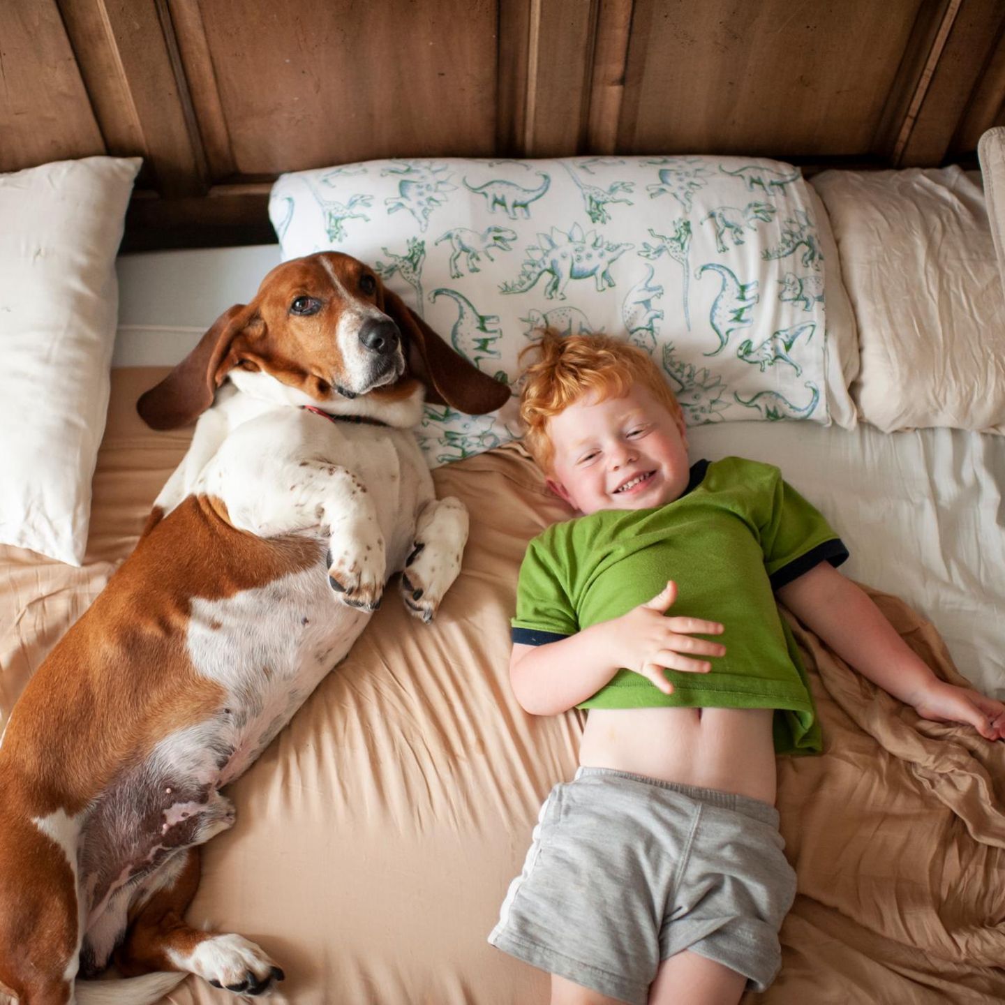 Kleiner Junge mit roten Haaren und Hund im Bett