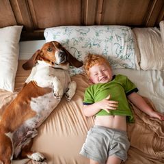 Kleiner Junge mit roten Haaren und Hund im Bett