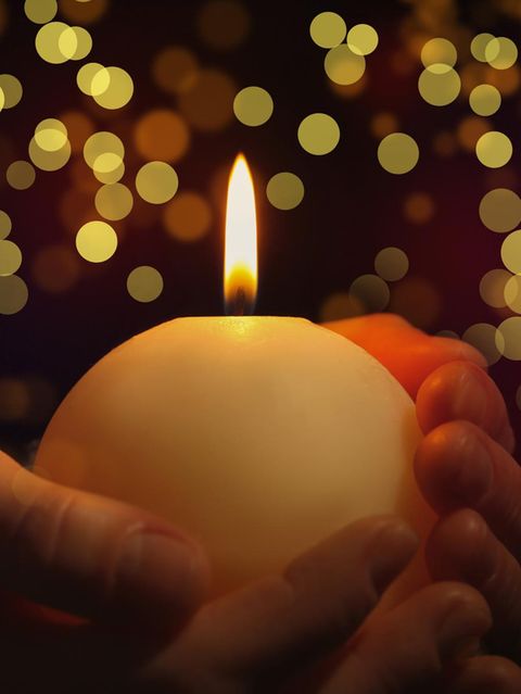 Hand hält Kerze  in weihnachtlicher Umgebung