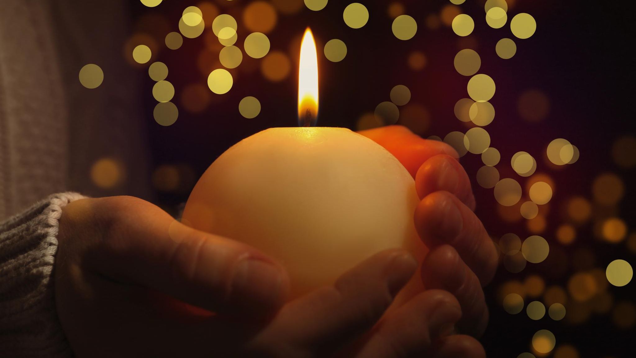 Hand hält Kerze  in weihnachtlicher Umgebung