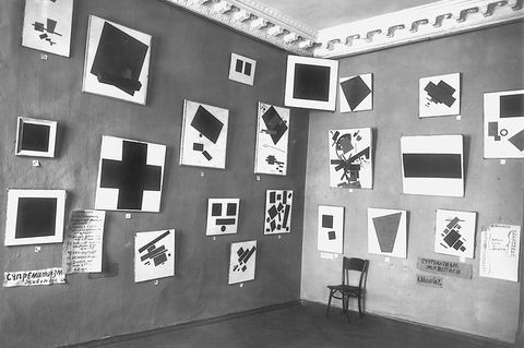 Blick in einem Galerieraum mit zahlreichen Bildern an den Wänden, in der Ecke das "Schwarze Quadrat"