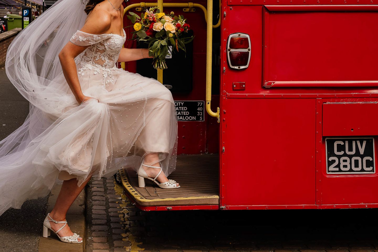 Eine Person in einem weißen Hochzeitskleid steigt in eine rote Straßenbahn