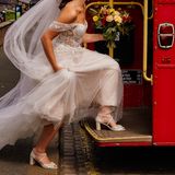 Eine Person in einem weißen Hochzeitskleid steigt in eine rote Straßenbahn