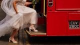 Eine Person in einem weißen Hochzeitskleid steigt in eine rote Straßenbahn