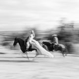 Zwei Personen reiten in Hochzeitskleidung auf Pferden