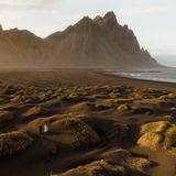 Ein hügeliger Küstenabschnitt, durch den zwei Menschen laufen