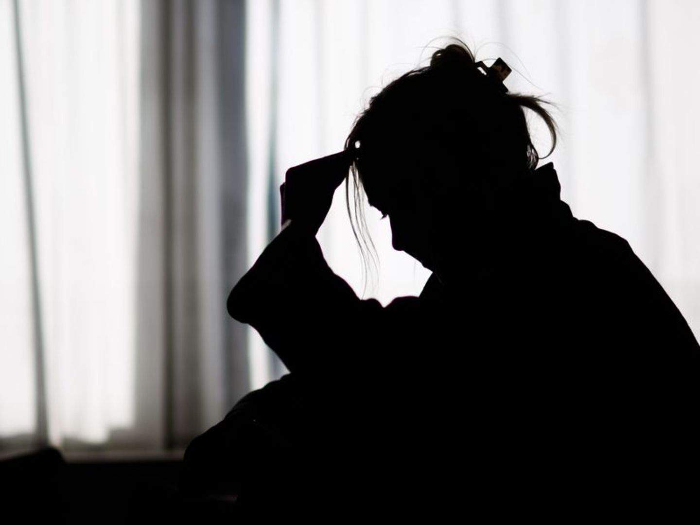 Silhouette einer Frau vor einer hellen Fensterfront