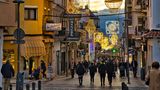 Straße mit Menschen, Läden und Weihnachtsbeleuchtung