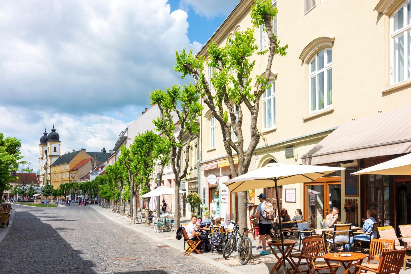 Straße und rechts im Bild Lokal, im Hintergrund Piaristenkirche von Trenčín