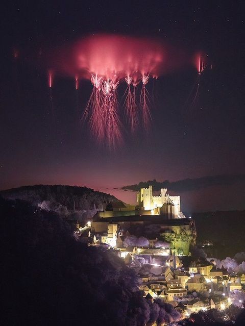 Rote Kobolde am Nachthimmel über Burg Beynac