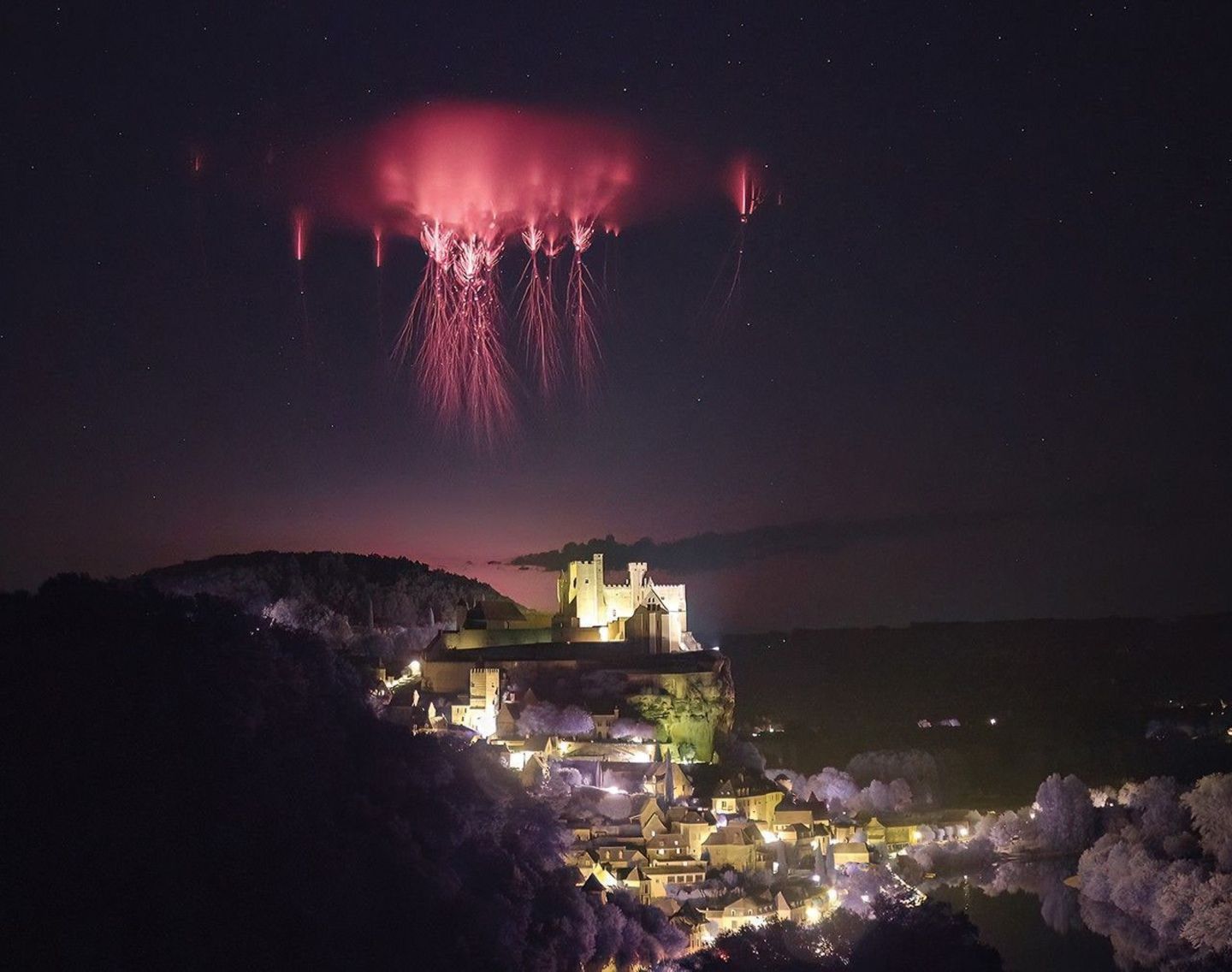 Rote Kobolde am Nachthimmel über Burg Beynac