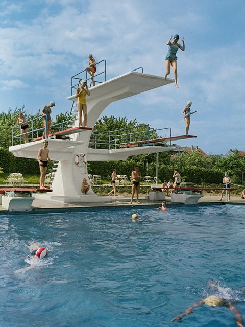 Personen springen von einem Sprungturm im Freibad