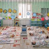 Kinder liegen in einem Zimmer, über ihnen schweben Luftballons