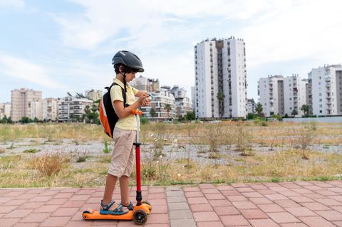 Junge mit Roller auf dem Weg zur Schule