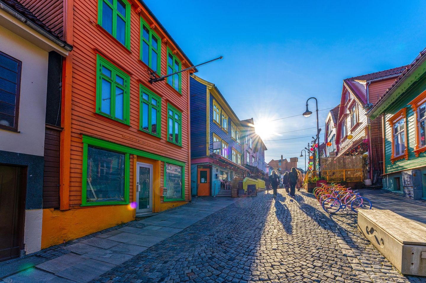 So knallbunt wie hier wird es sonst nirgends: Stavangers wohl bekannteste Straße und kunterbunte Visitenkarte ist die Øvre Holmegate – auch „Fargegaten“ genannt – und ein toller Ausgangspunkt für einen Stadtbummel. Hausfassaden in Pink, Türkis und Sonnengelb, kleine Läden mit kuratiertem Angebot, Cafés mit nordischem Flair, Kunsthandwerk und jede Menge perfekte Fotospots machen sie zu einem lebhaften Treffpunkt. Nur wenige Schritte weiter zeigt Stavanger sein historisches Gesicht: Nahe des Hafens liegt der mittelalterliche Dom der Stadt, die älteste Bischofskirche des Landes. Wer zum Bummel aufbricht, sollte unbedingt einen Abstecher in die Altstadt („Gamle Stavanger“) machen, denn sie gilt als die am besten erhaltene Holzhaussiedlung Nordeuropas. An verwinkelten, gepflasterten Gassen reihen sich hier 173 teils leicht schiefe, weiß gestrichene Holzhäuser aneinander, geschmückt mit üppigen Blumen in Vorgärten und Außenbereichen – besonders zwischen Frühling und Sommer ein Spaziergang wie durch ein Freilichtmuseum. Wer noch tiefer in die Geschichte eintauchen möchte, fährt hinaus zum Hafrsfjord, wo das monumentale Denkmal „Sverd i fjell“ aufragt. Drei gewaltige Schwerter ragen dort aus dem felsigen Grund und erinnern an die Schlacht von 872, als Harald Schönhaar Norwegen geeint haben soll. Die Klingen stehen symbolisch für Frieden, Einheit und Freiheit.