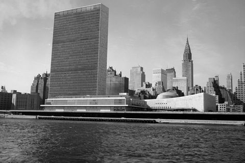 Schwarz-weiß Fotografie eines rechteckigen Wolkenkratzers am Flussufer von Manhattan, 1950er Jahre