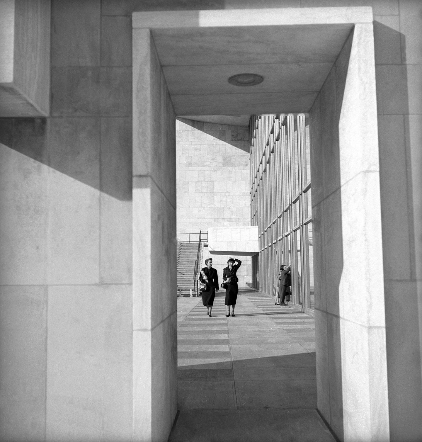 Frauen gehen an einer Fensterfassade entlang; schwarz-weiß Foto, 1951